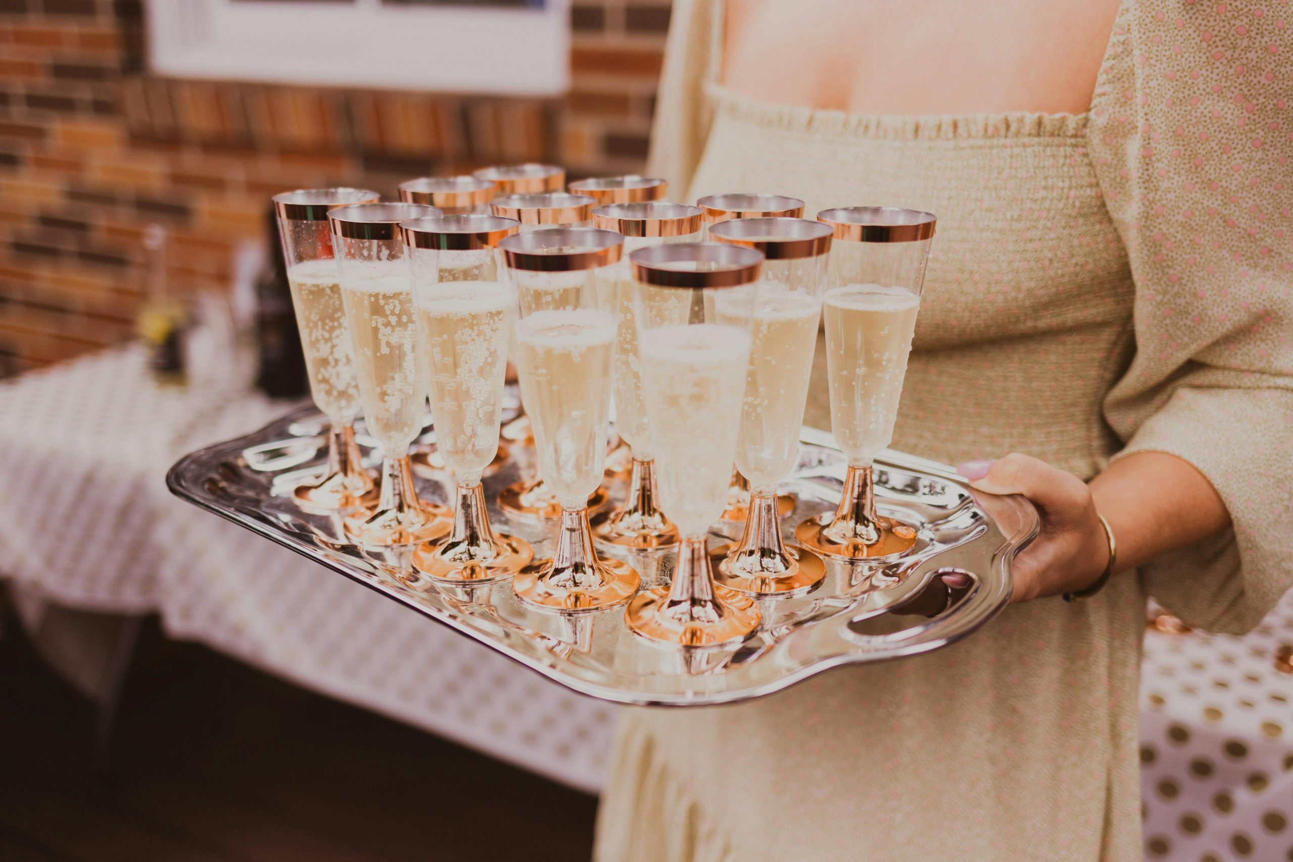 A tray of champagne flutes carried by a woman at an elegant indoor party.